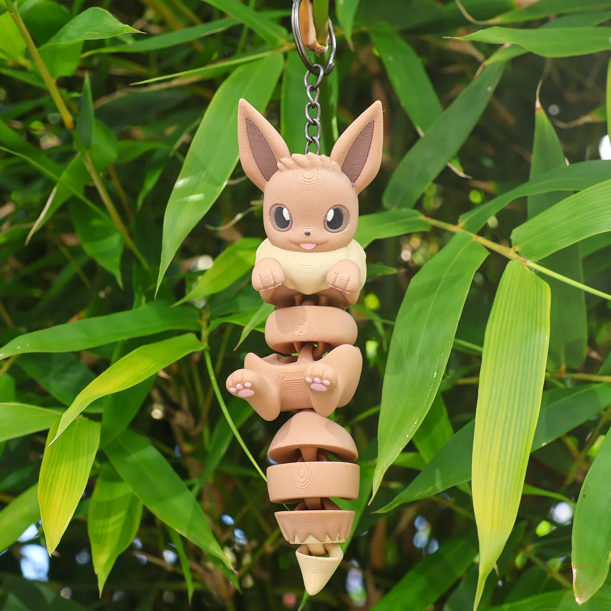 3D printed Eevee flexi articulated keychain hanging from bamboo